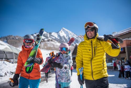 a group of people standing in the snow with snowboards at Grand Lodge 1-Bedroom Condo with 3 Queens & Close to Everything condo in Crested Butte