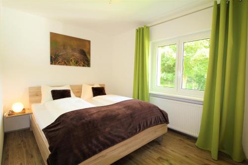 a bedroom with a large bed with green curtains at Appartements Cilli in Neukirchen am Großvenediger