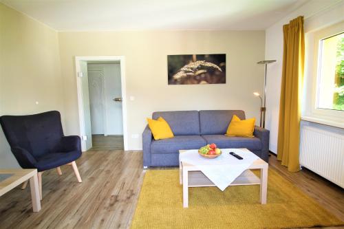 a living room with a blue couch and a table at Appartements Cilli in Neukirchen am Großvenediger