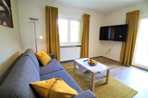 a living room with a blue couch and a table at Appartements Cilli in Neukirchen am Großvenediger