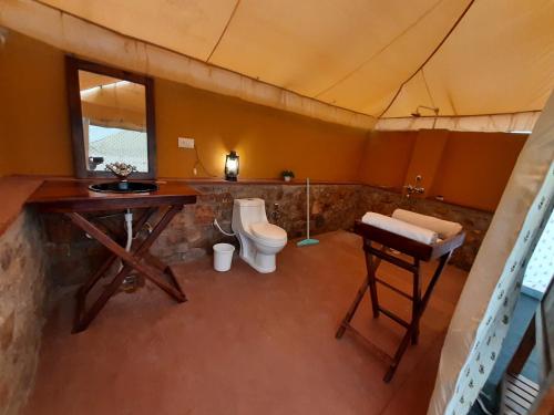 a bathroom with a toilet and a table and a sink at Ranthambhore Bagh Dwar Camp in Khilchipur