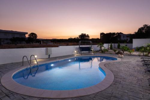 einen Pool in einem Garten mit Sonnenuntergang im Hintergrund in der Unterkunft Dama Dama Villas in Gennadi