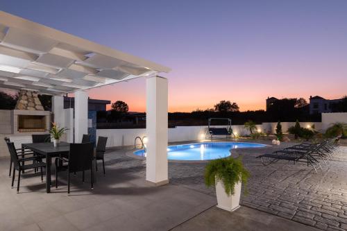 a patio with a table and chairs and a pool at Dama Dama Villas in Gennadi