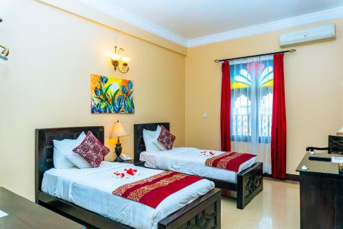 a bedroom with two beds and a window at Golden Tulip Stone Town Boutique in Zanzibar City