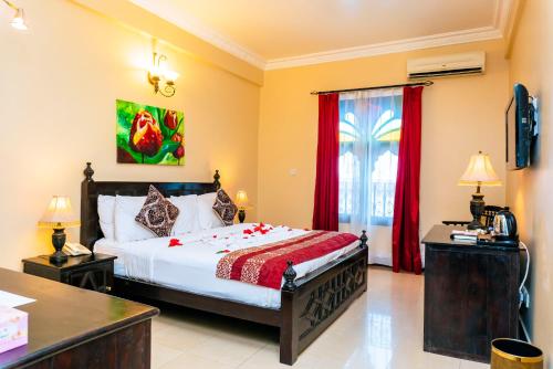 a bedroom with a large bed with red curtains at Golden Tulip Stone Town Boutique in Zanzibar City