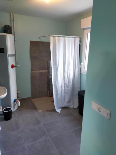a bathroom with a shower with a white shower curtain at Maison individuelle neuve plein pied avec terrasse et jardin clos 10minutes a pied de la plage in Quiberville