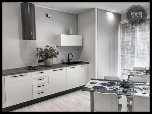 a kitchen with white cabinets and a table with chairs at Il Viaggiatore B&B in San Giorgio delle Pertiche