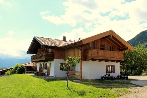 a house with a wooden roof on a green field at Schneiderhof Urlaub auf dem Bauernhof in Bernau am Chiemsee