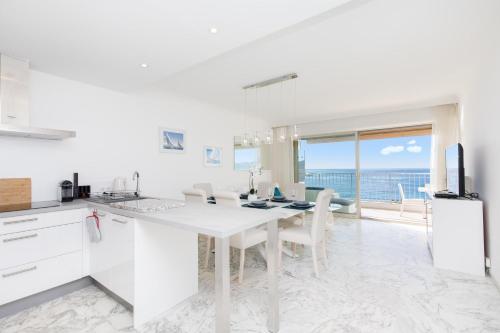 - une cuisine blanche avec une table à manger et une vue sur l'océan dans l'établissement On La Croisette deluxe 2 bedrooms 2 baths, à Cannes