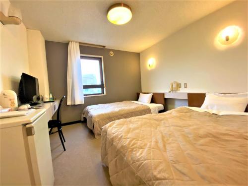 Habitación de hotel con 2 camas y escritorio con ordenador en Hotel Tetora, en Hakodate