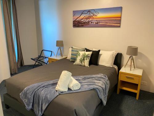 a bedroom with a bed with pillows and a painting at Mooloolaba Beachfront: Superior Resort Apartment in Mooloolaba