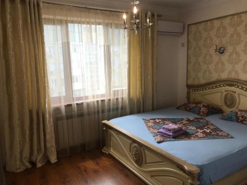 ein Schlafzimmer mit einem Bett mit einem großen Fenster in der Unterkunft 1 комнатная квартира в самом центре города на Жарбосынова 71 in Atyrau