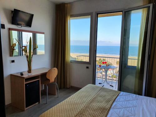 リミニにあるHotel Tilmarのベッド1台、海を望むバルコニーが備わるホテルルームです。