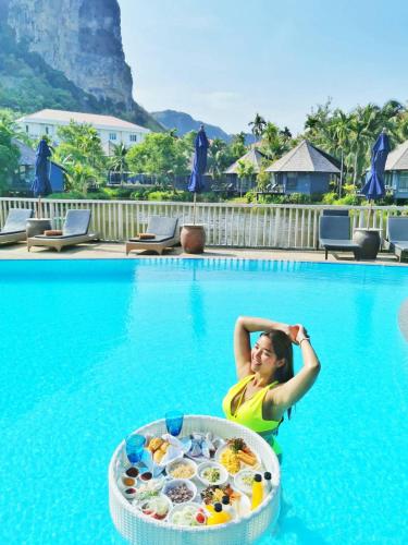 Eine Frau im Schwimmbecken mit einem Tisch voller Essen in der Unterkunft Peace Laguna Resort & Spa in Ao Nang Beach