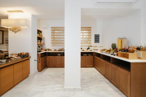 a kitchen with wooden cabinets and a white wall at Cyano Hotel in Plakias
