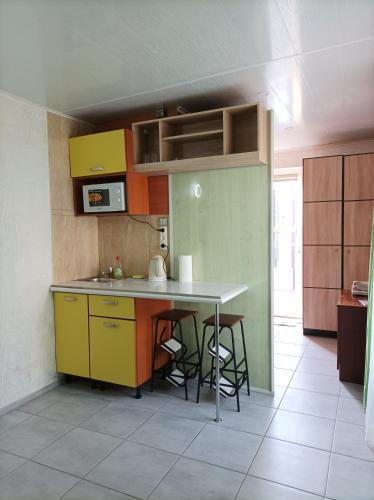 a kitchen with yellow and green cabinets and a table at House&House 84 in Petropavlovskaya Borshchagovka