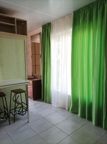 a room with green curtains and a table and a window at House&House 84 in Petropavlovskaya Borshchagovka