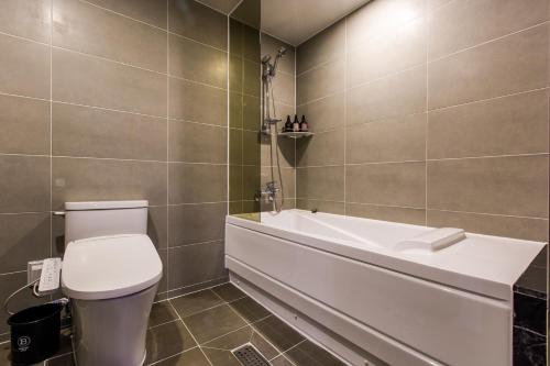 a bathroom with a toilet and a bath tub at Brown-Dot Hotel Songdo in Busan