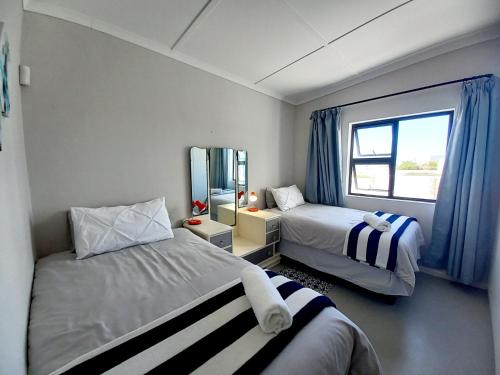 Habitación pequeña con 2 camas y ventana en Orca Cottage, en St Helena Bay