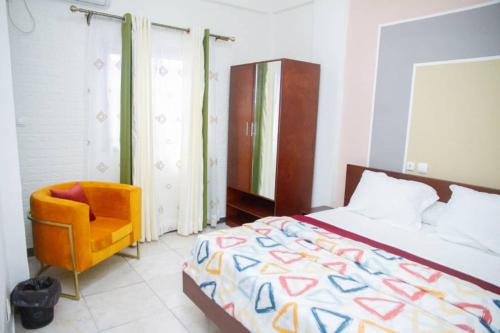 - une chambre avec un lit et une chaise jaune dans l'établissement ABT Apartments Bonapriso-7Mins From Airport, à Douala