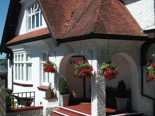 a white house with flower pots on the front of it at The Red House Guest House in Falmouth