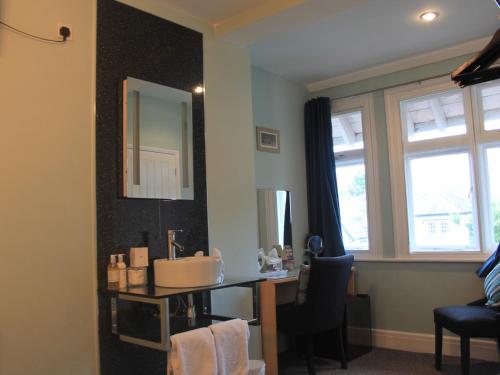 a bathroom with a sink and a desk with a mirror at The Red House Guest House in Falmouth