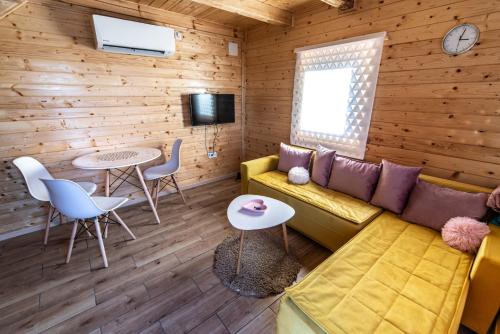 a living room with a couch and a table and chairs at Brvnare MADERA Banja Ždrelo in Ždrelo