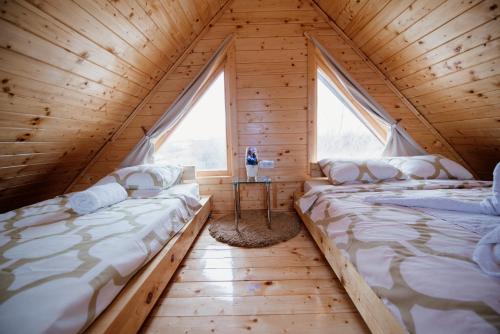 two beds in a wooden room with two windows at Brvnare MADERA Banja Ždrelo in Ždrelo