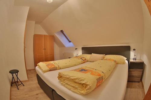 a bedroom with a large bed with yellow sheets at Pension Edlinger in Sankt Georgen ob Murau