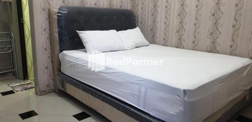 ein Bett mit einem schwarzen Kopfteil und weißen Kissen darauf in der Unterkunft Homestay MM Syariah RedPartner in Sidoarjo