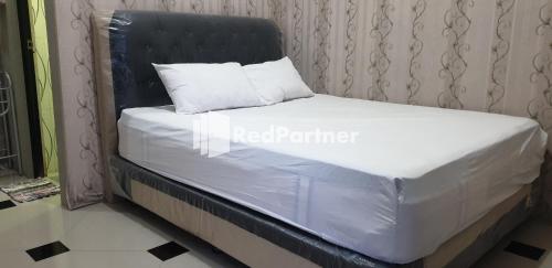 ein Bett mit einem schwarzen Kopfteil und einem weißen Kissen in der Unterkunft Homestay MM Syariah RedPartner in Sidoarjo