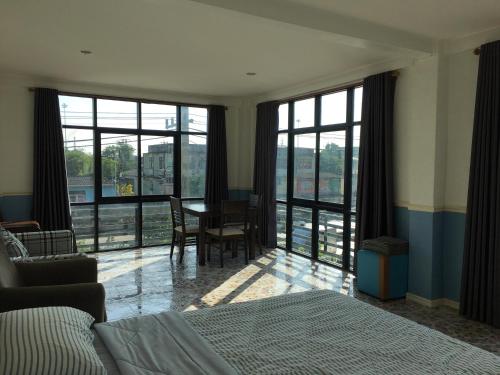 sypialnia z łóżkiem, biurkiem i oknami w obiekcie Baanmali Ari w mieście Pathum Thani