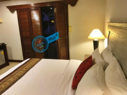 a white bed with a red pillow in a room at Le Tanjong House in Patong Beach