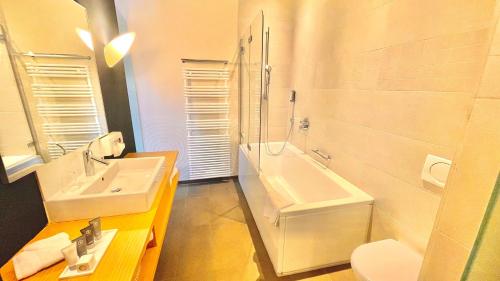a bathroom with a sink and a tub and a toilet at Parkhotel du Sauvage in Meiringen
