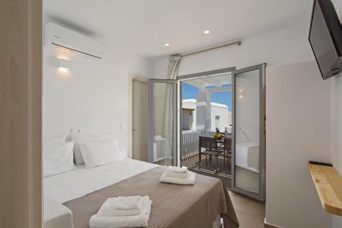 Barbarigos luxury spa apartments في ناوسا: غرفة نوم بيضاء مع سرير وشرفة