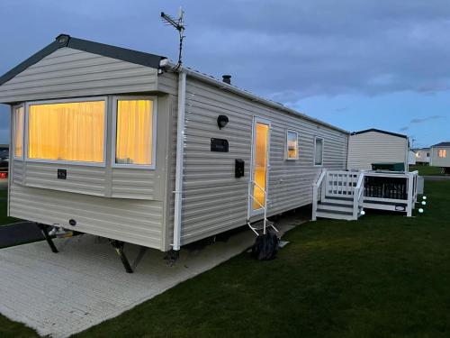 a gray tiny house sitting on a lawn at Holiday Park Caravan Fluffy in Harts Holiday Park in Leysdown-on-Sea