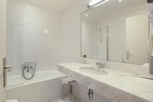 a bathroom with a sink and a tub and a mirror at HOTEL DU PRINTEMPS in Paris