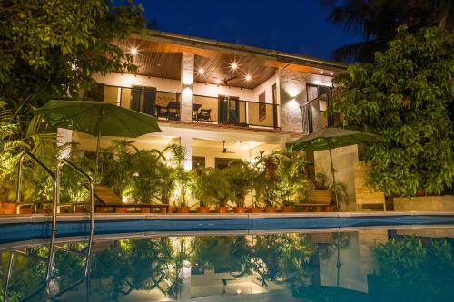 una casa con piscina por la noche en Sanidhya Beach Resort, en Alibaug