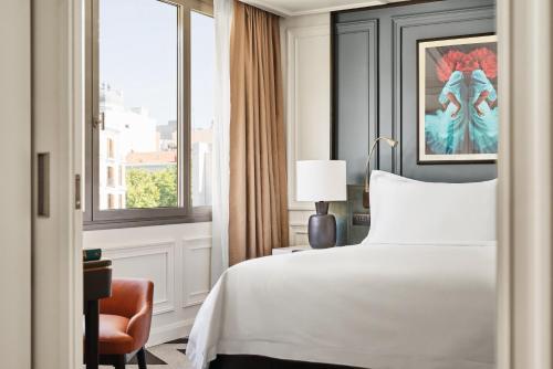 a bedroom with a bed and a chair and a window at Rosewood Villa Magna in Madrid
