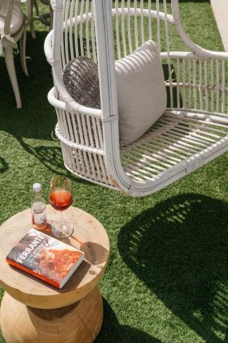 a table with a book and a glass of wine and a chair at Cyano Hotel in Plakias