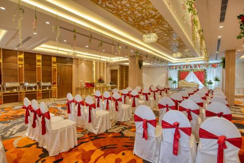 a banquet hall with white chairs and red bows at Hotel Deep Clarks Inn Lucknow in Lucknow