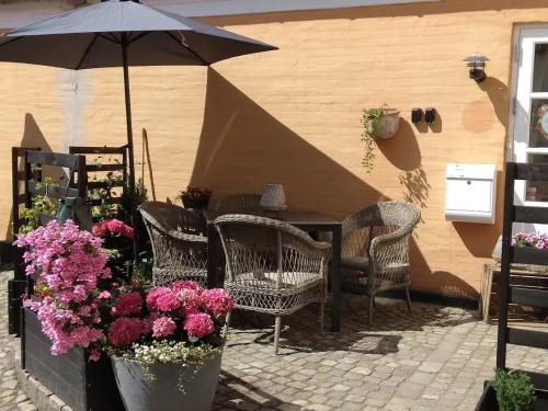 a patio with chairs and an umbrella and flowers at HosHelle in Ribe