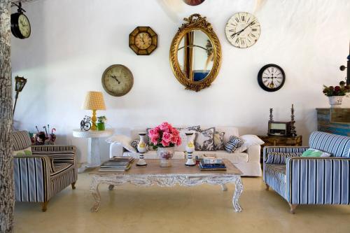 a living room with clocks on the wall and a table at Pousada Bendito Seja in Praia do Espelho