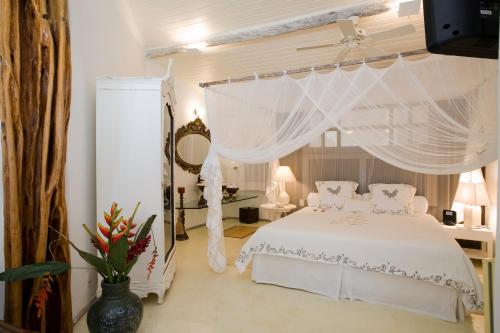 um quarto com uma cama de dossel branca em Pousada Bendito Seja em Praia do Espelho