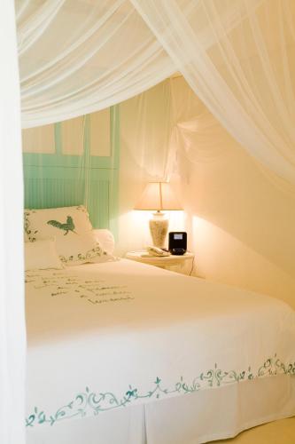a bedroom with a white bed with a canopy at Pousada Bendito Seja in Praia do Espelho
