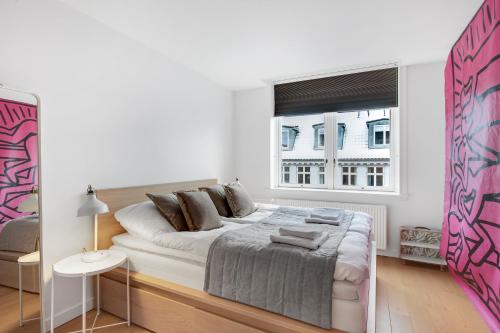 a white bedroom with a large bed and a window at Sanders Monarch - Charming One-Bedroom Apartment With Two Balconies in Copenhagen