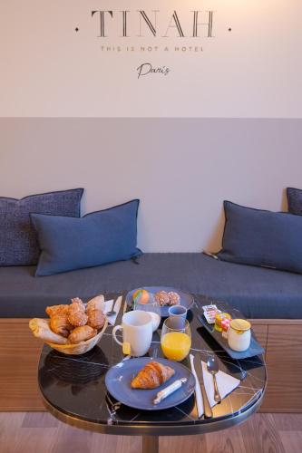 - une table basse avec des aliments pour le petit-déjeuner sur un canapé dans l'établissement Tinah Paris, Aboukir, à Paris