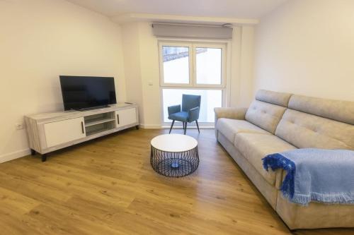 a living room with a couch and a television at Apartamentos Centro Llanes in Llanes