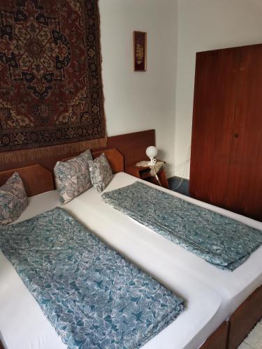 two twin beds in a bedroom with a rug at Villa-Negra Retro Panzió in Balatonföldvár