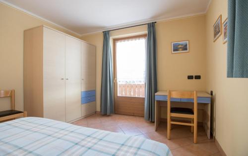 Schlafzimmer mit einem Bett, einem Schreibtisch und einem Fenster in der Unterkunft Stefano 1 in Livigno
